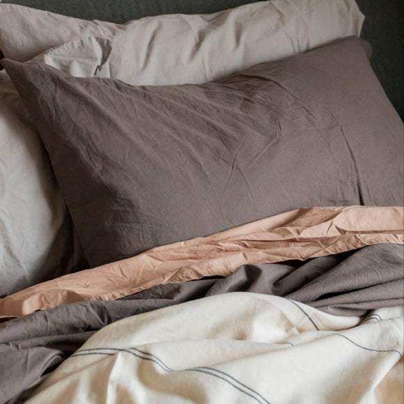 Stack of folded beige, brown, and gray bedding on a dark surface