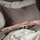 Stack of folded beige, brown, and gray bedding on a dark surface