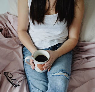  Girl on bed holding a mug of coffee 