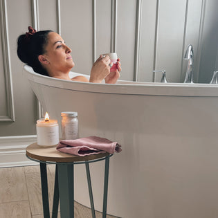  woman enjoying bath with tea and candle