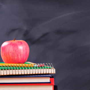  A red apple on top of school books with a chalk background