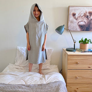  Little boy wearing Poncho standing on a twin bed